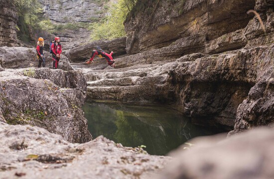 Ein Mann springt beim Canyoning in Salzburg von einer Klippe ins Wasser
