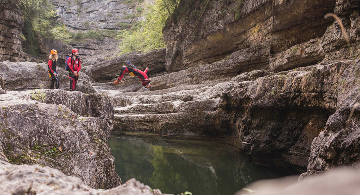 Ein Mann springt beim Canyoning in Salzburg ins Wasser