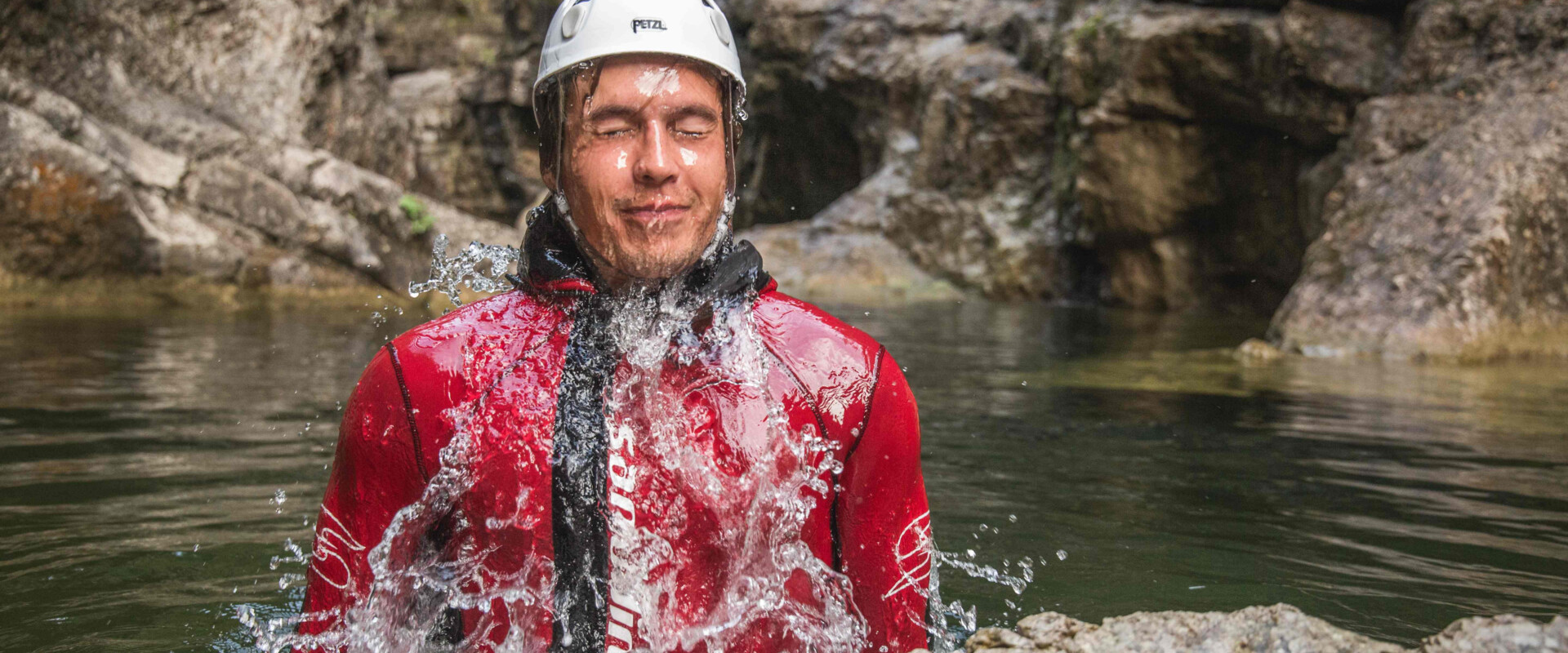 Ein Mann taucht bei den individuellen Canyoning-Touren aus dem Wasser
