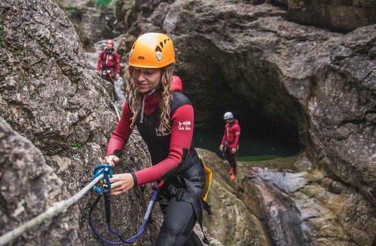 Beim Canyoning für Familien weist der Guide einen Mann bezüglich der Sicherung ein