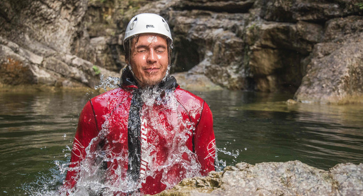 Ein Mann taucht bei den individuellen Canyoning-Touren aus dem Wasser