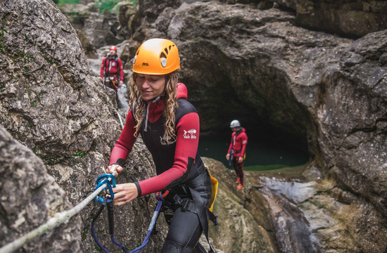 Eine junge Frau überprüft beim Canyoning in der Strubklamm die Sicherung