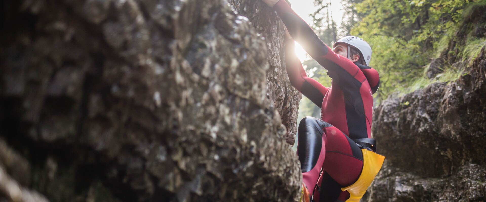 Ein Mann klettert beim Canyoning in der Strubklamm die Felswand hinauf