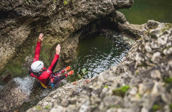 Ein Mann rutscht beim Canyoning in der Strubklamm auf den nassen Steinen ins Wasser