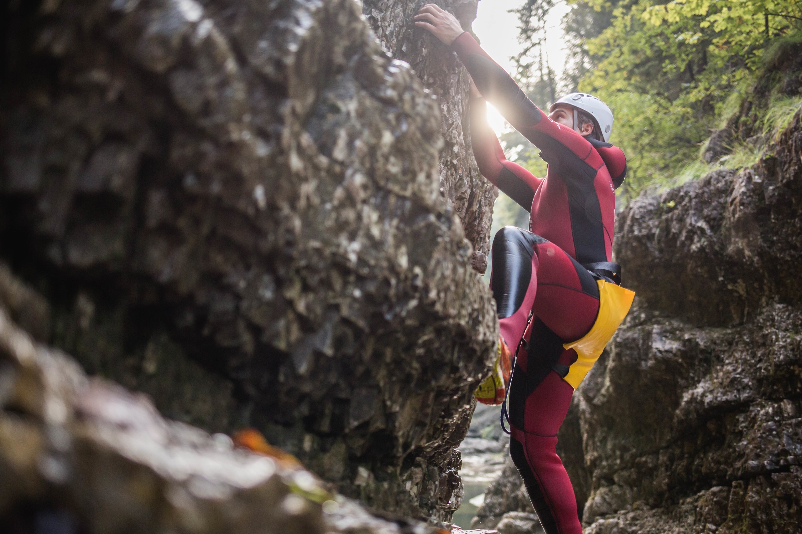 Ein Mann klettert beim Canyoning in der Strubklamm die Felswand hinauf