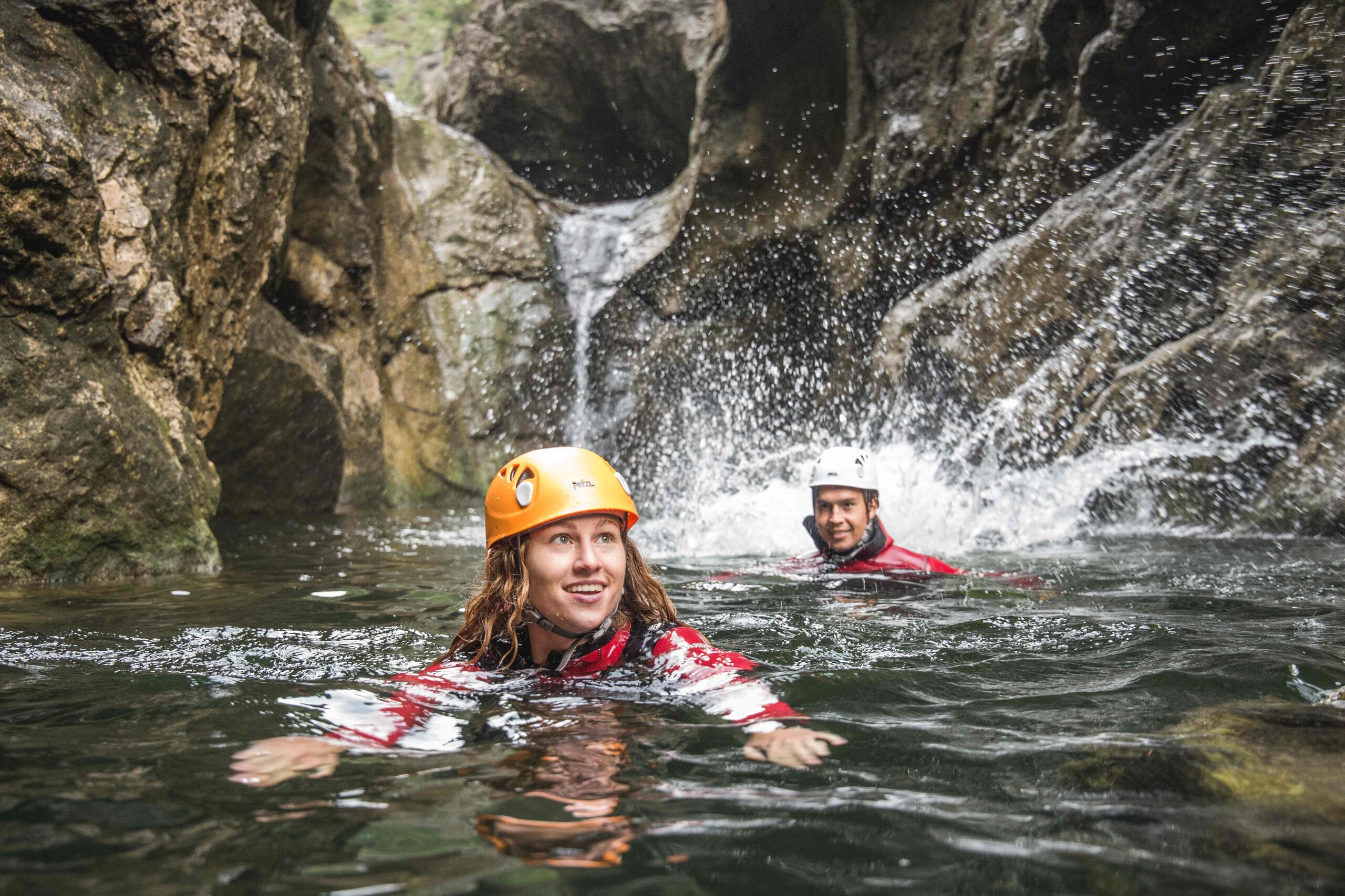 Ein Mann und eine Frau schwimmen beim Canyoning im Aktivurlaub im Salzkammergut durch die Klamm