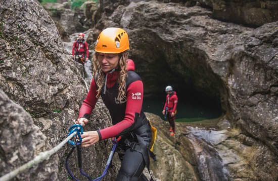 Eine junge Frau überprüft beim Canyoning in Salzburg die Sicherung