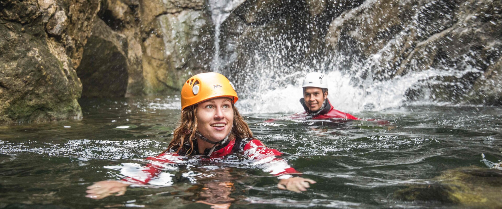 Ein Mann und eine Frau schwimmen beim Canyoning im Aktivurlaub im Salzkammergut durch die Klamm