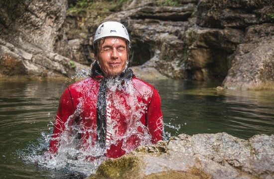 Ein Mann taucht beim Canyoning im Salzkammergut aus dem Wasser