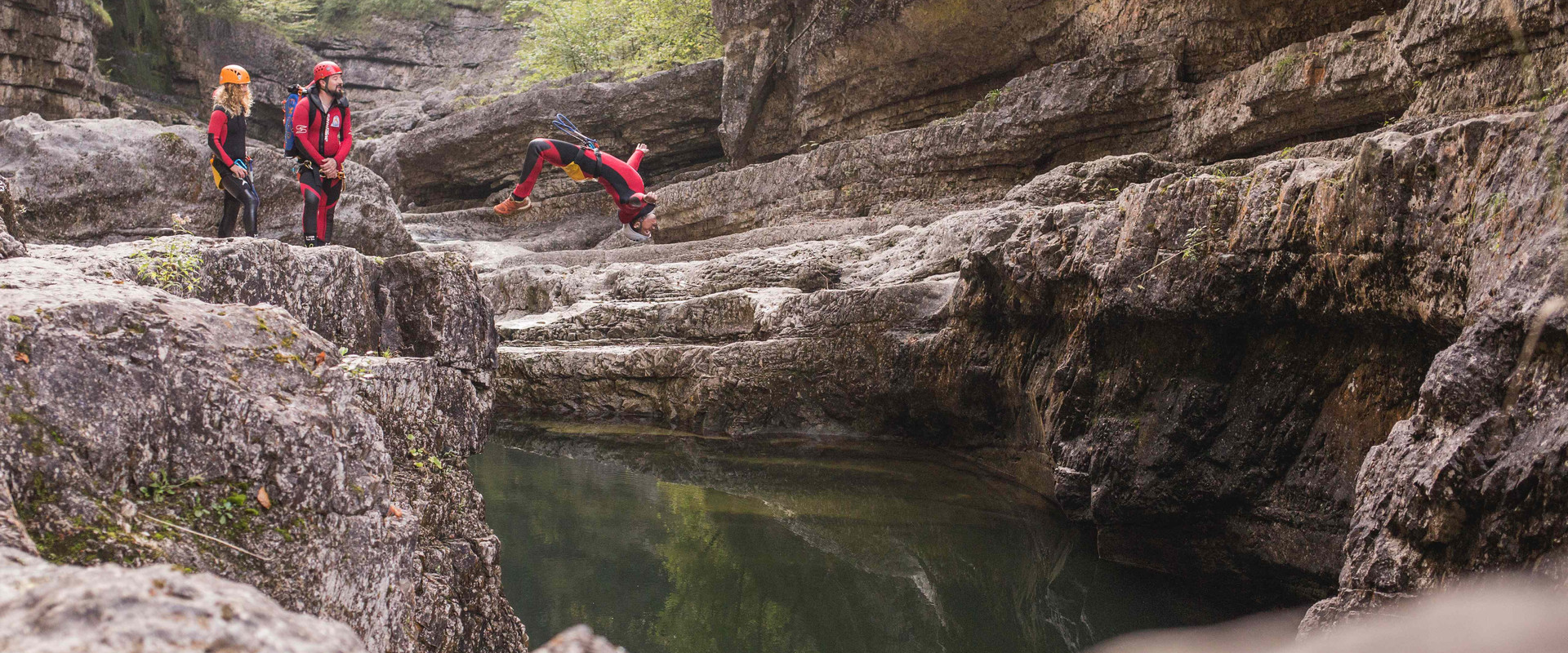 Ein Mann springt beim Canyoning in Salzburg von einer Klippe ins Wasser