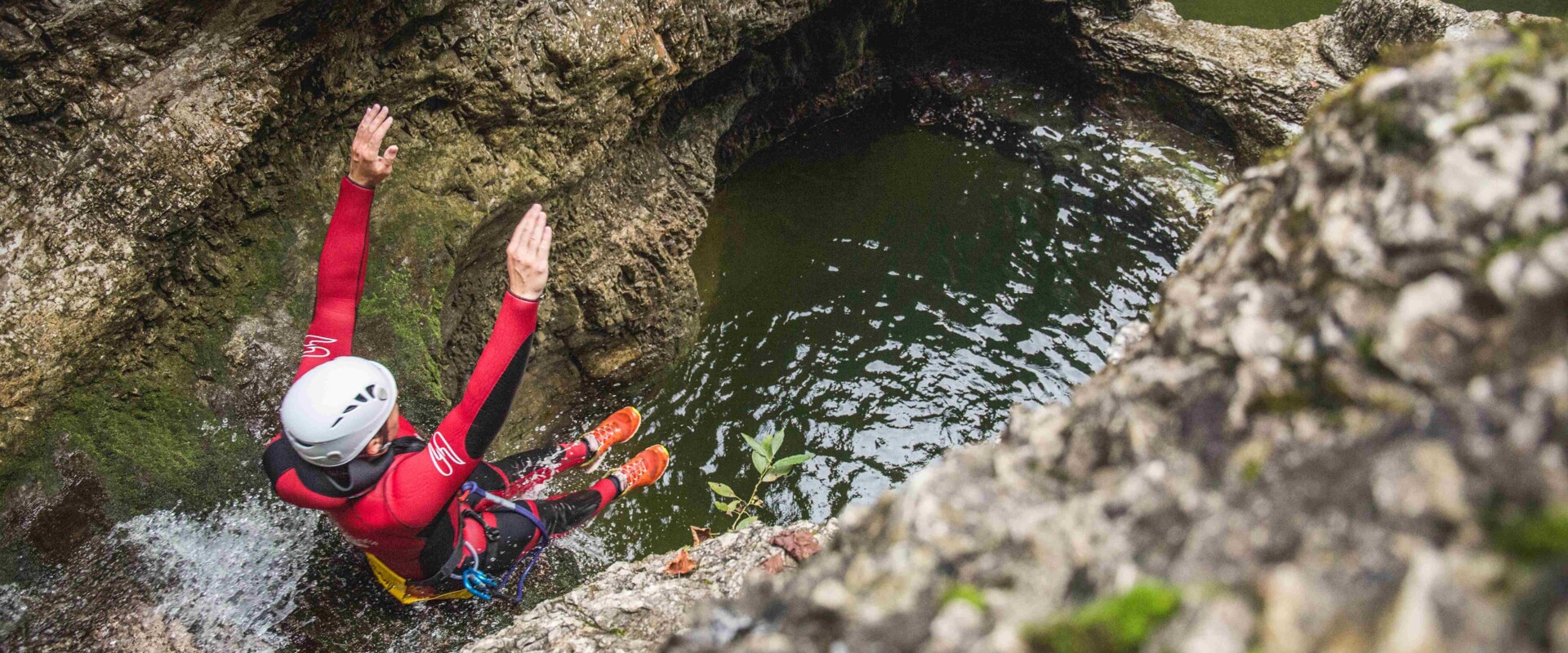 Ein Mann rutscht beim Canyoning in Salzburg auf den nassen Steinen ins Wasser